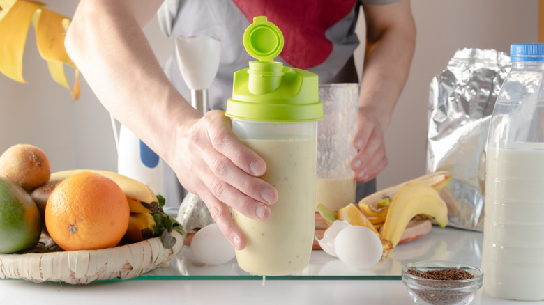 Hand holding a protein shaker filled with thick liquid