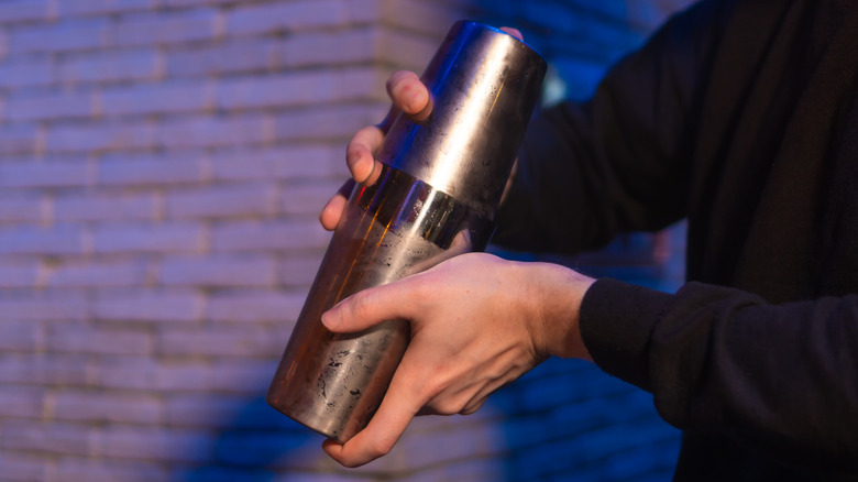 Two hands holding a cocktail shaker
