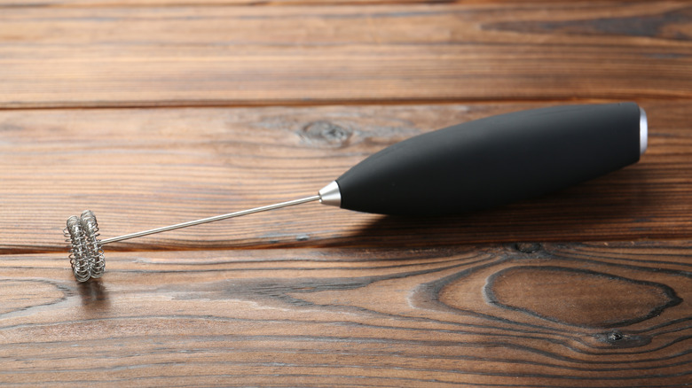 Black handheld frother on wood background