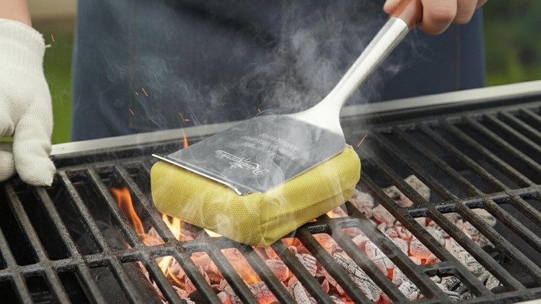 Someone cleans the grill with a steam brush.