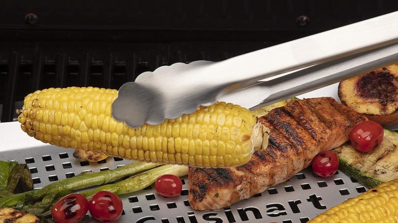 Cuisinart﻿ steel tongs pick up an ear of corn.