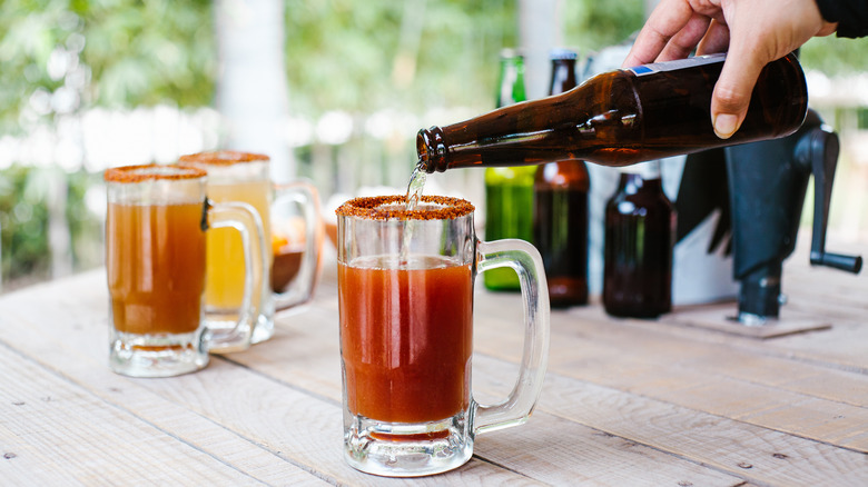 hand pouring beer into michelada