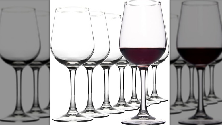 Several wine glasses, one if filled with red wine.