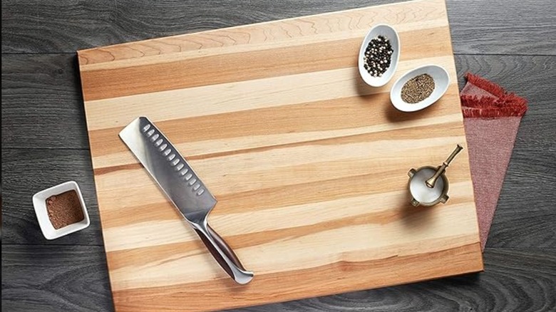 A wooden chopping board on top of a red cloth.