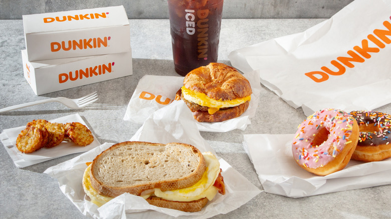 Assortment of Dunkin' Donuts breakfast offerings, including donuts, breakfast sandwiches and coffee.