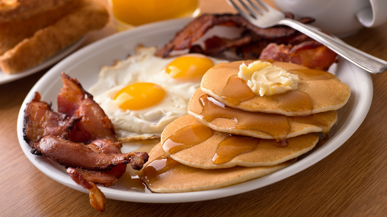 Appetizing breakfast platter with pancakes, eggs, and bacon.