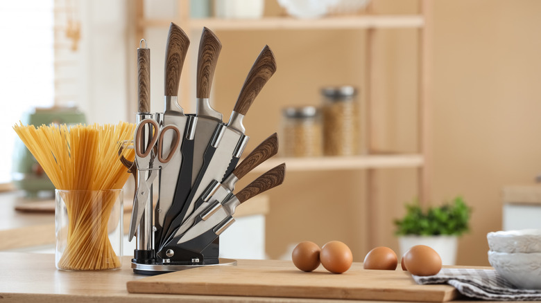 Set of knives on a magnetic block on countertop next to pasta and eggs