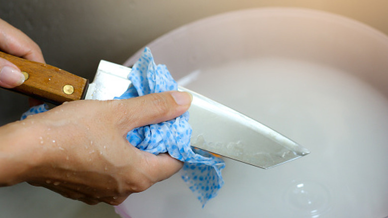 Closeup of woman's hands handwashing a kitchen knife
