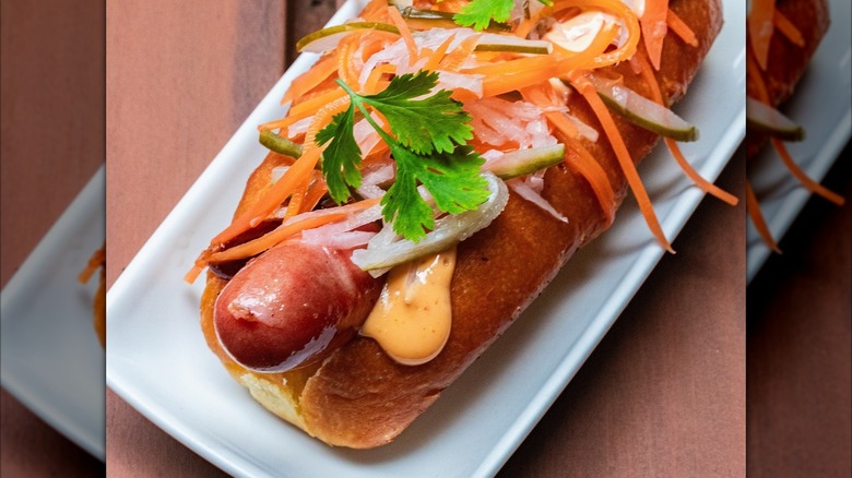 A hot dog has banh-mi style toppings