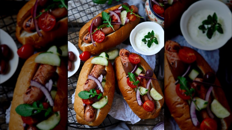 sausages topped with cucumber, tomato, red onion, and olives.