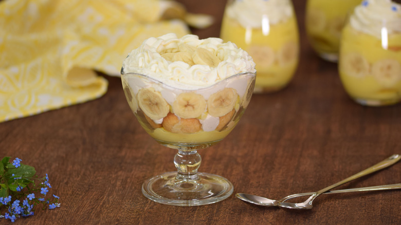 bBanana pudding is served in a glass dish next to two spoons.
