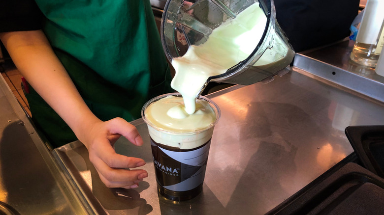Starbucks barista pouring cold foam into beverage