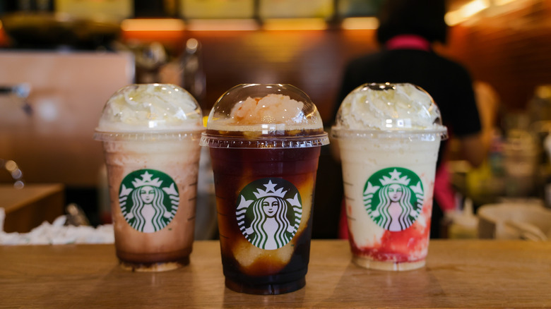 three Starbucks Frappuccinos with whipped cream and toppings