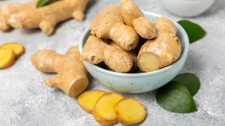 Whole and chopped chunks of fresh ginger in a bowl on counter
