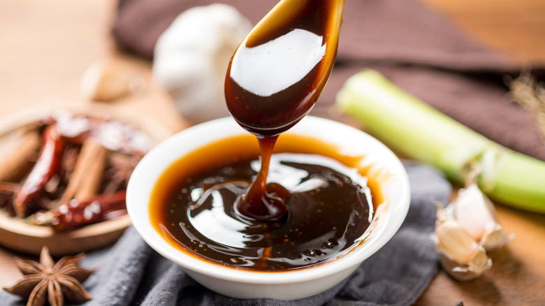 Oyster sauce on a spoon next to aromatics
