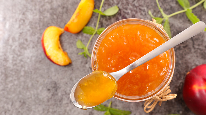 Peach jam with peach slice on countertop
