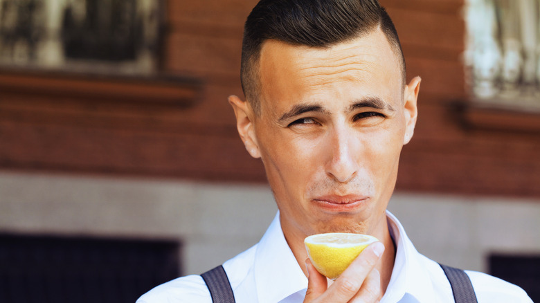 A man puckers his face while eating a lemon