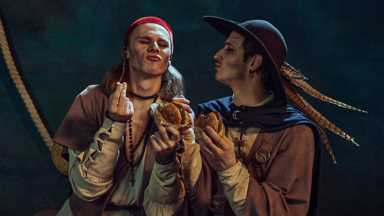 Two people dressed as pirates eating fast food burgers