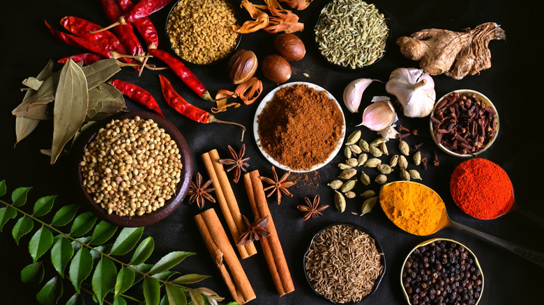 A collection of spices, both ground and dried, against a black table