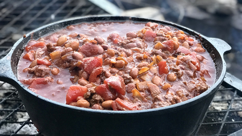 A pot of chili cooks on an outdoor stove.