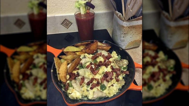 A Hangtown Fry omelet is shown in a skillet in front of a bloody mary.