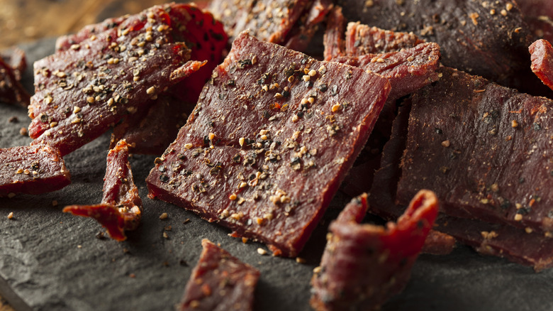 Black pepper-crusted beef jerky is stacked in a pile.