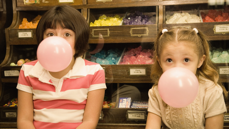 Vintage-looking photo of two young girls in a candy store blowing bubbles