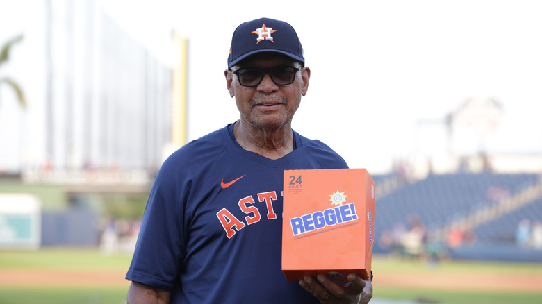 Reggie Jackson in an Astros uniform in a ballpark holds a box of Reggie! bars.