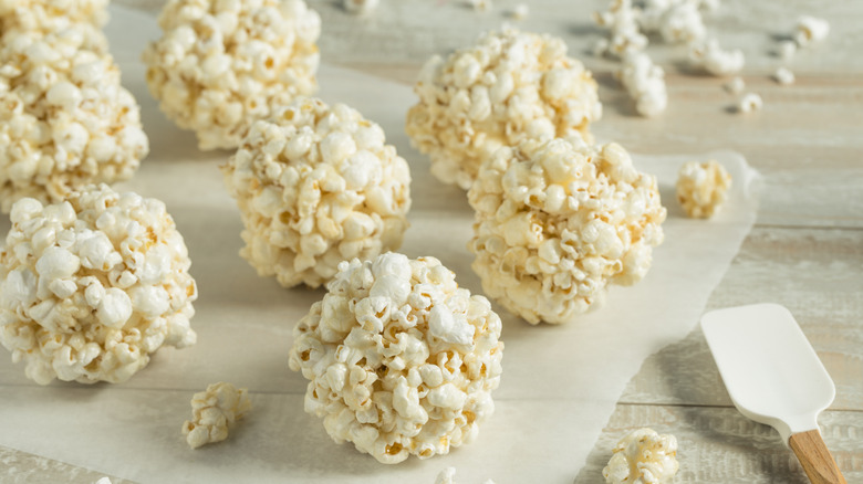 several popcorn ball treats on parchment paper next to a rubber spatula