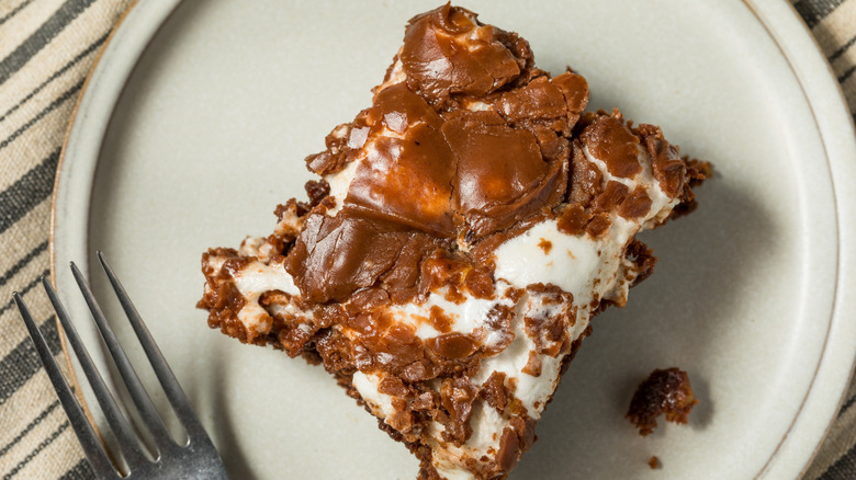 top down photo of a brownie with swirled marshmallow topping on a plate with a fork next to it
