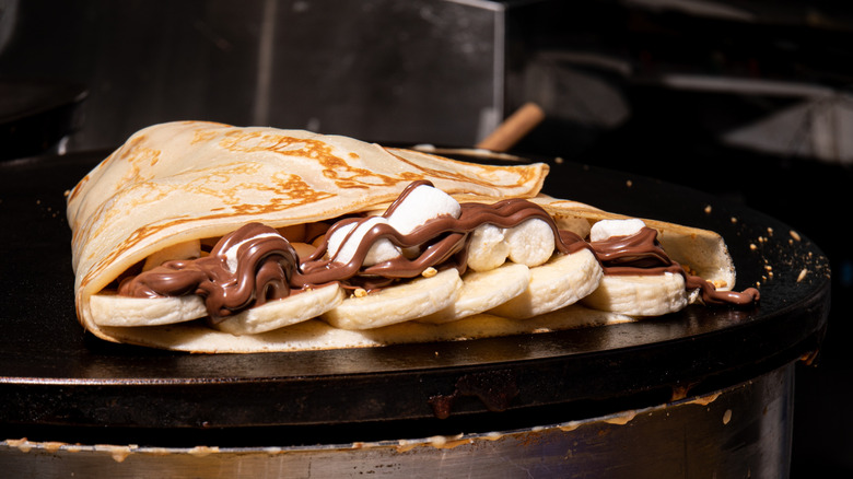 closeup of a crepe filled with chocolate sauce, bananas, and marshmallows