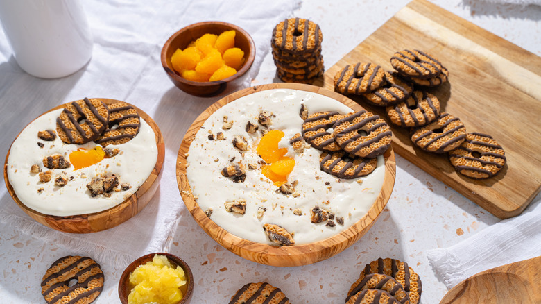 creamy dessert dip bowls with cookies and fruit scattered around on cutting boards