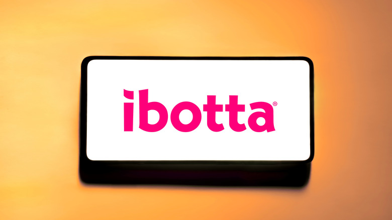 Smartphone showing Ibotta logo, sitting on an orange background