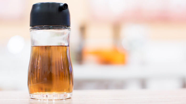 clear glass container of fish sauce, black top 