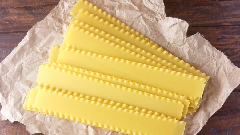 dried lasagna noodles spread across crumpled paper on wood surface