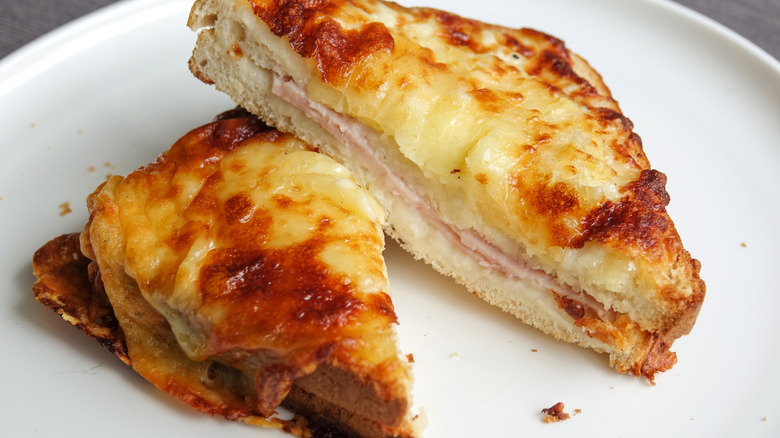 Halved Croque monsieur sandwich smothered with cheese on a white plate