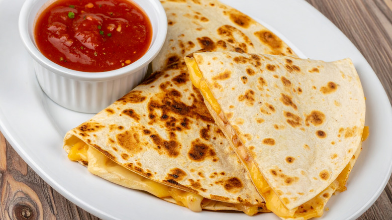 Cheese quesadilla on a white plate with a side of salsa
