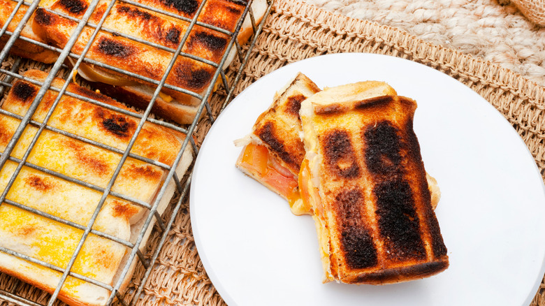 Charred Braaibroodjie sandwiches in a grilling grate and on a white plate