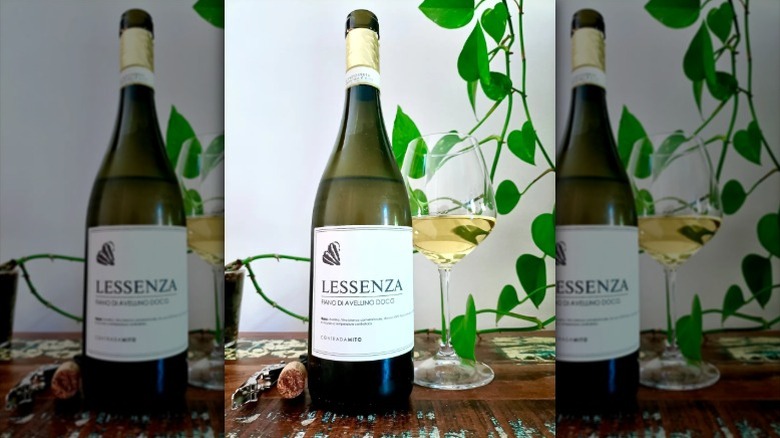 A bottle of fiano di avellino wine sits next to a wine glass on a wooden table