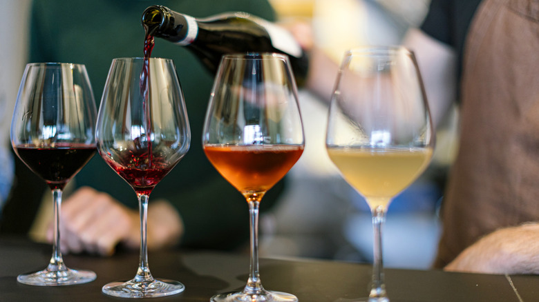 Four wine glasses sit in a row filled with different varieties of wine