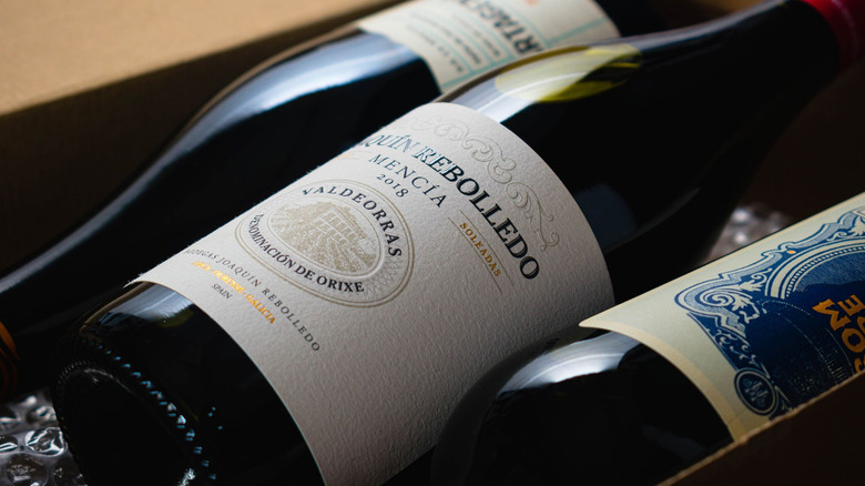 Three wine bottles lie in a box ready to be shipped