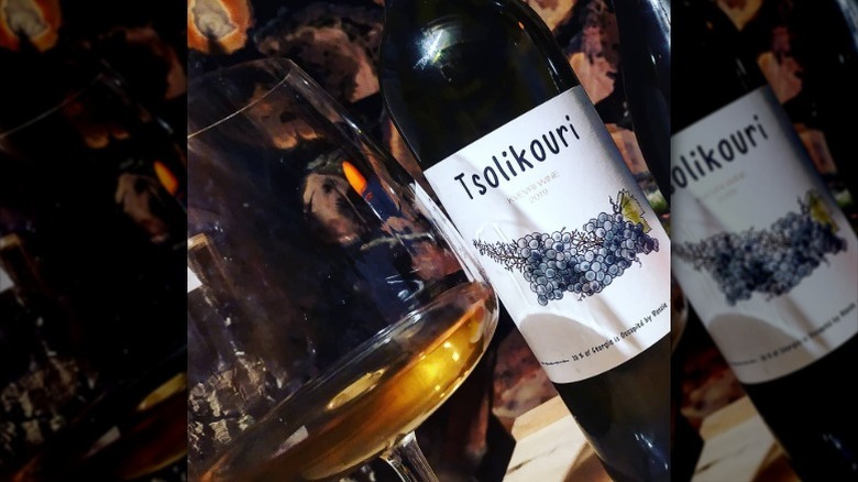 Closeup of a bottle of tsolikouri wine next to a wine glass