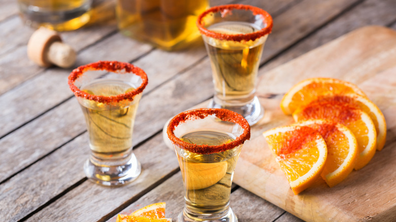 Shots of mezcal with chili rims and orange slices