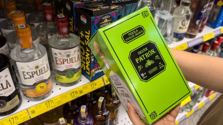 Hands selecting box of Patron tequila in store
