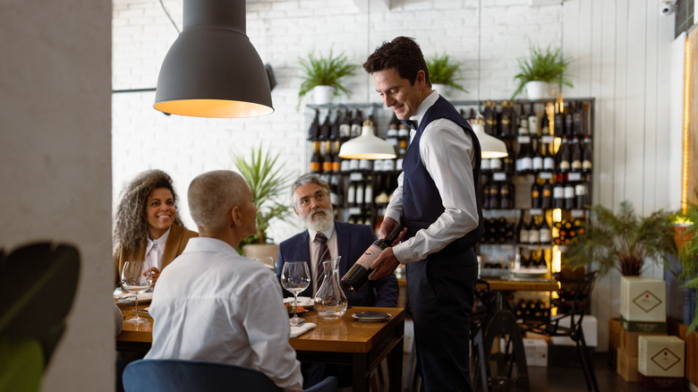 sommelier showing wine bottle to diners