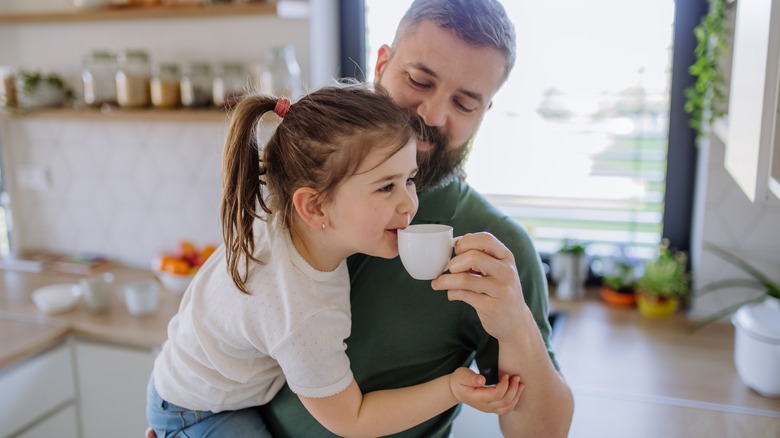 Man holding girl feeding her coffee
