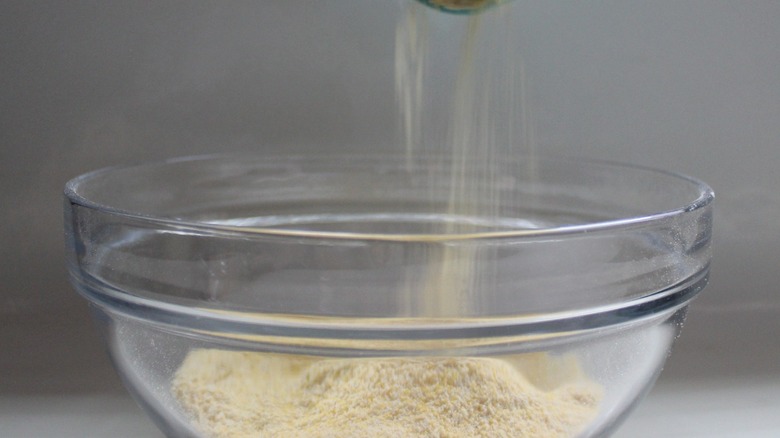 pouring cornmeal in a bowl