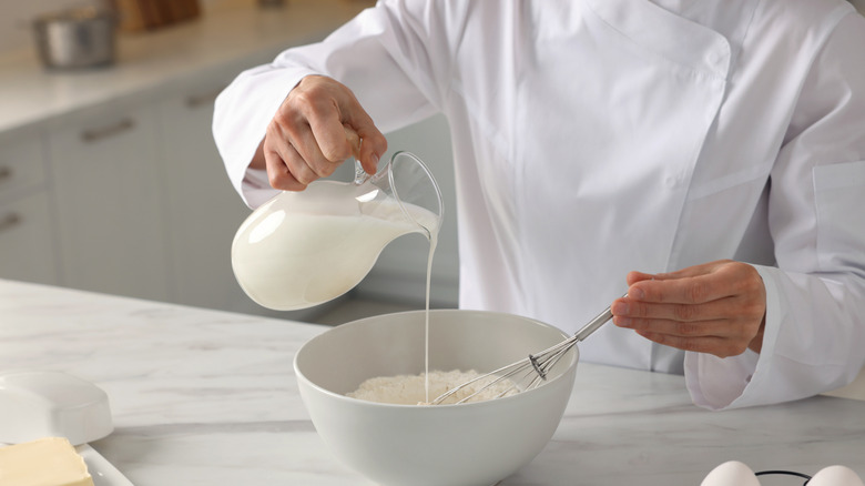 Chef adding milk into dough