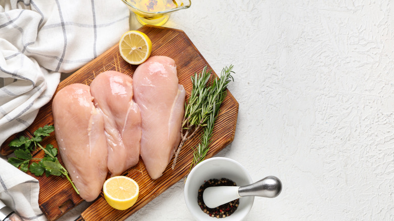 Wooden board with raw chicken breast