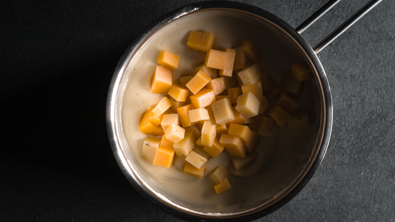 Cubed cheese added to a béchamel in a saucepan